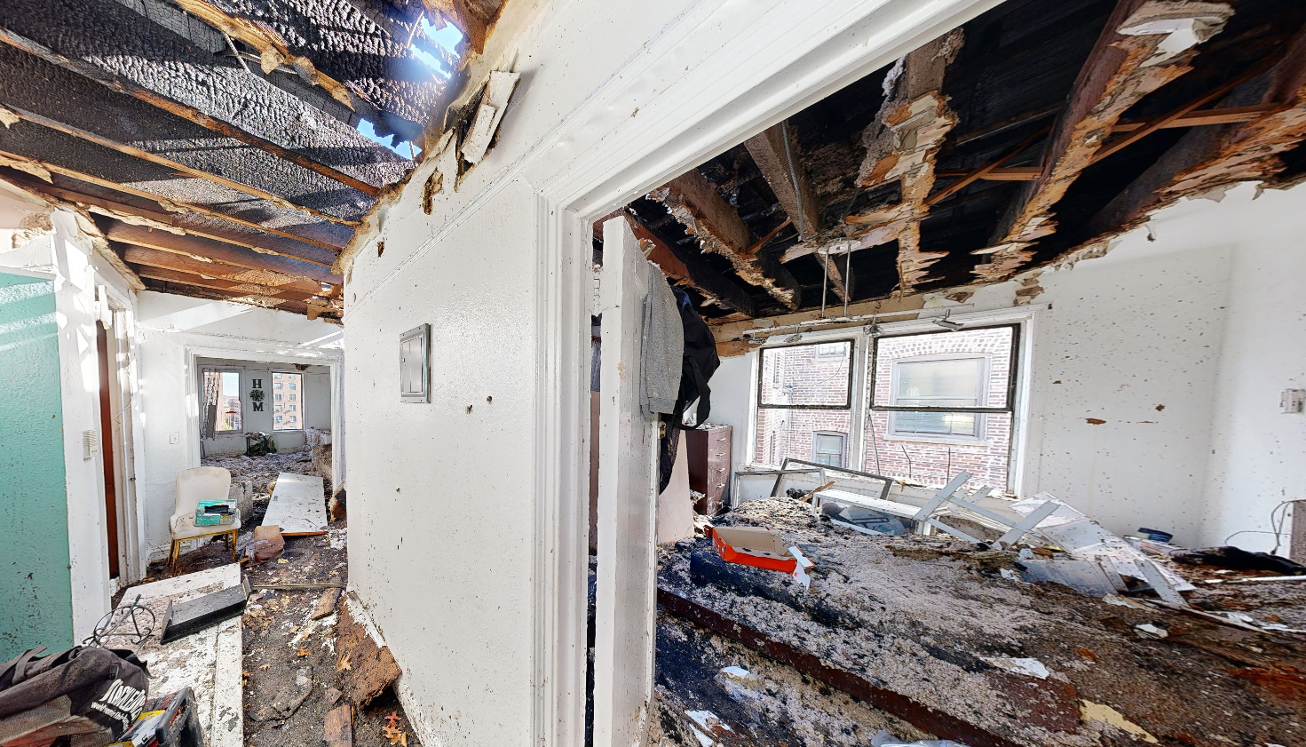 Severe residential fire damage with structural ceiling collapse and charred beams requiring emergency engineering assessment